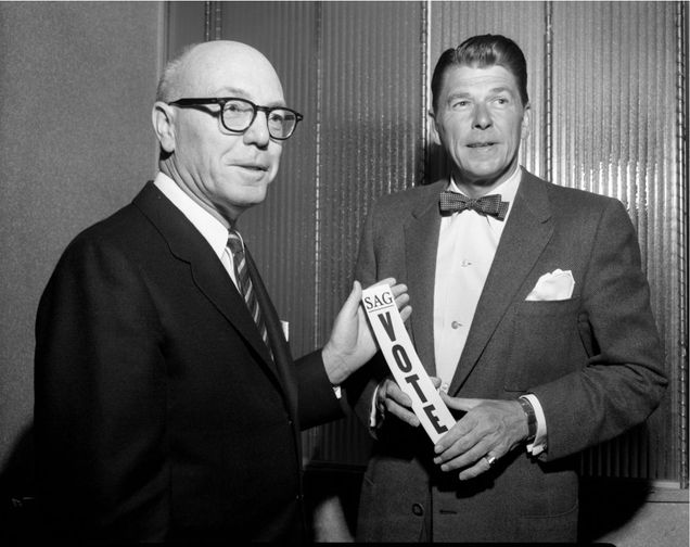 Two men hold a small placard that says "SAG Vote." Black and white.