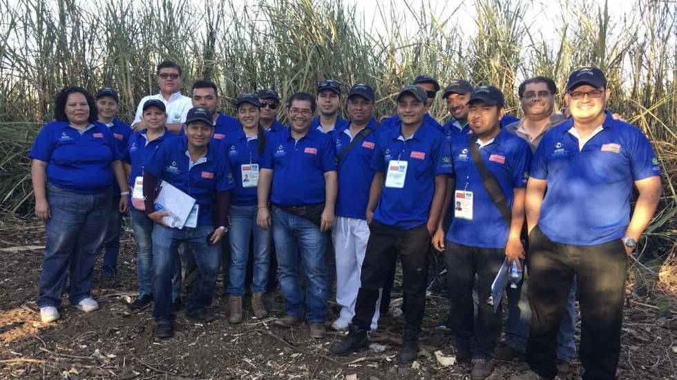 A picture of El Salvador Team agains a cane sugar field background.