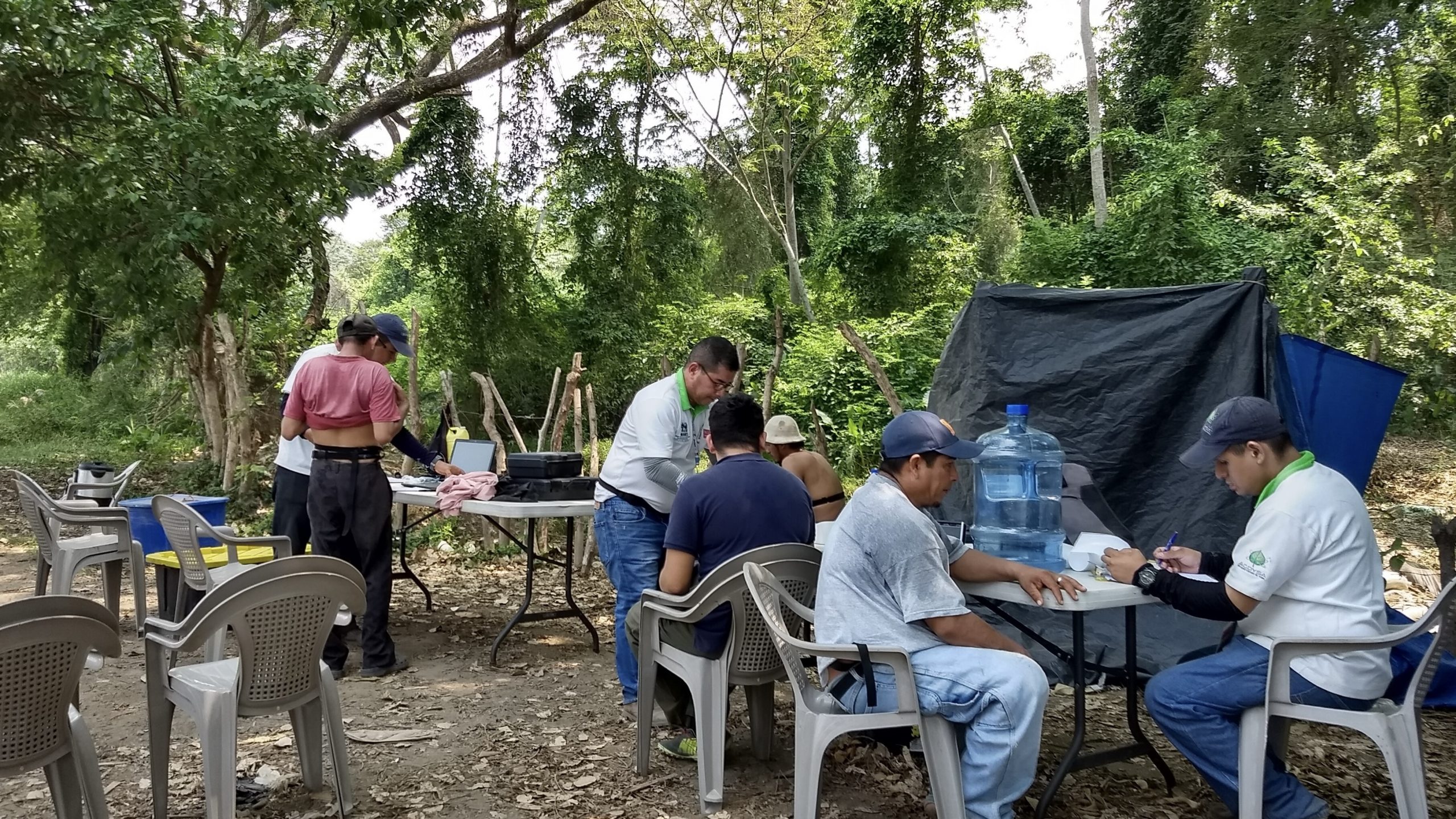 picture of fieldwork in Nicaragua. a participant has a device around his stomach, a second and third participants are sitting down while a team member monitors them, a fourth participant is being interviewed by a team member.