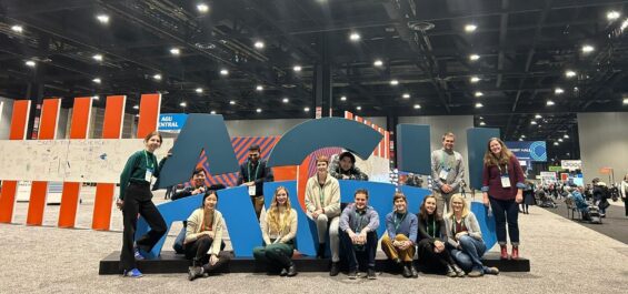 CCH affiliates and others stand in front of a large sign of the letters "AGU" at the American Geophysical Union conference.