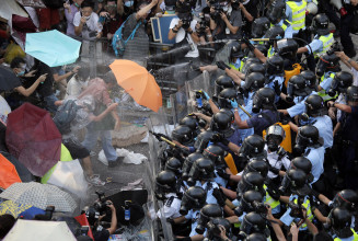 Riot police use pepper spray against protesters after thousands of people block a main road to the financial central district outside the government headquarters in Hong Kong, Sunday, Sept. 28, 2014. A tense standoff between thousands of Hong Kong pro-democracy protesters and police warning of a crackdown spiraled into an extraordinary scene of chaos Sunday as the crowd jammed a busy road and clashed with officers wielding pepper spray. (AP Photo/Vincent Yu)