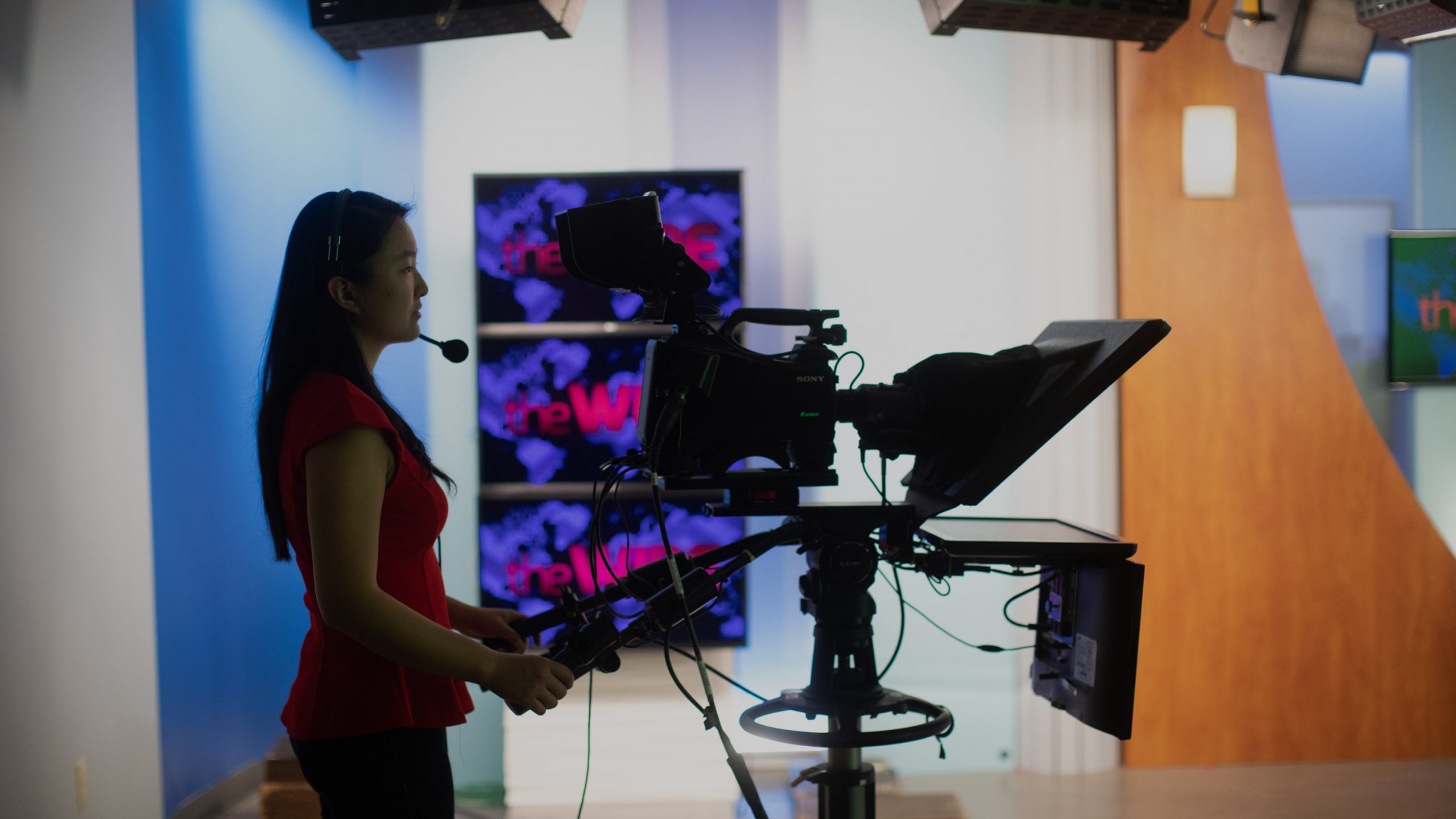 Woman operating camera in television studio.