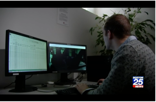 A researcher sitting in front of two monitors, analyzing and coding data.