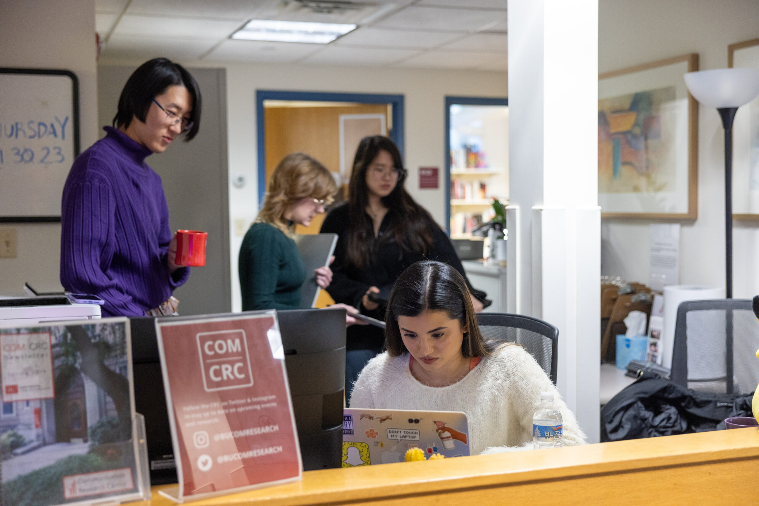 The CRC staff behind the reception desk in various stages of working and communication.