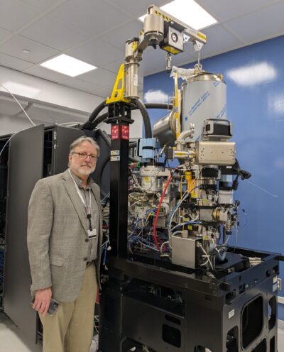 professor standing beside cryoEM microscope showing the inner workings of the instrument