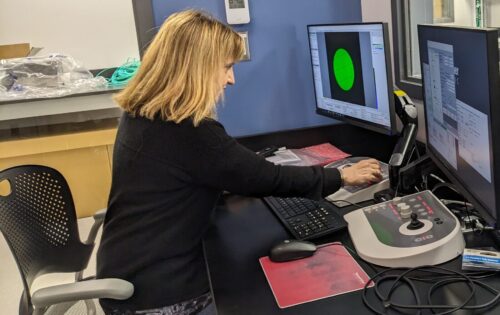 professor adjusting the settings of a cryoEM microscope using the control pads. 