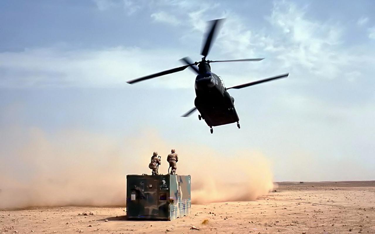 image from gulf war with a helicopter flying over two soldiers in the desert