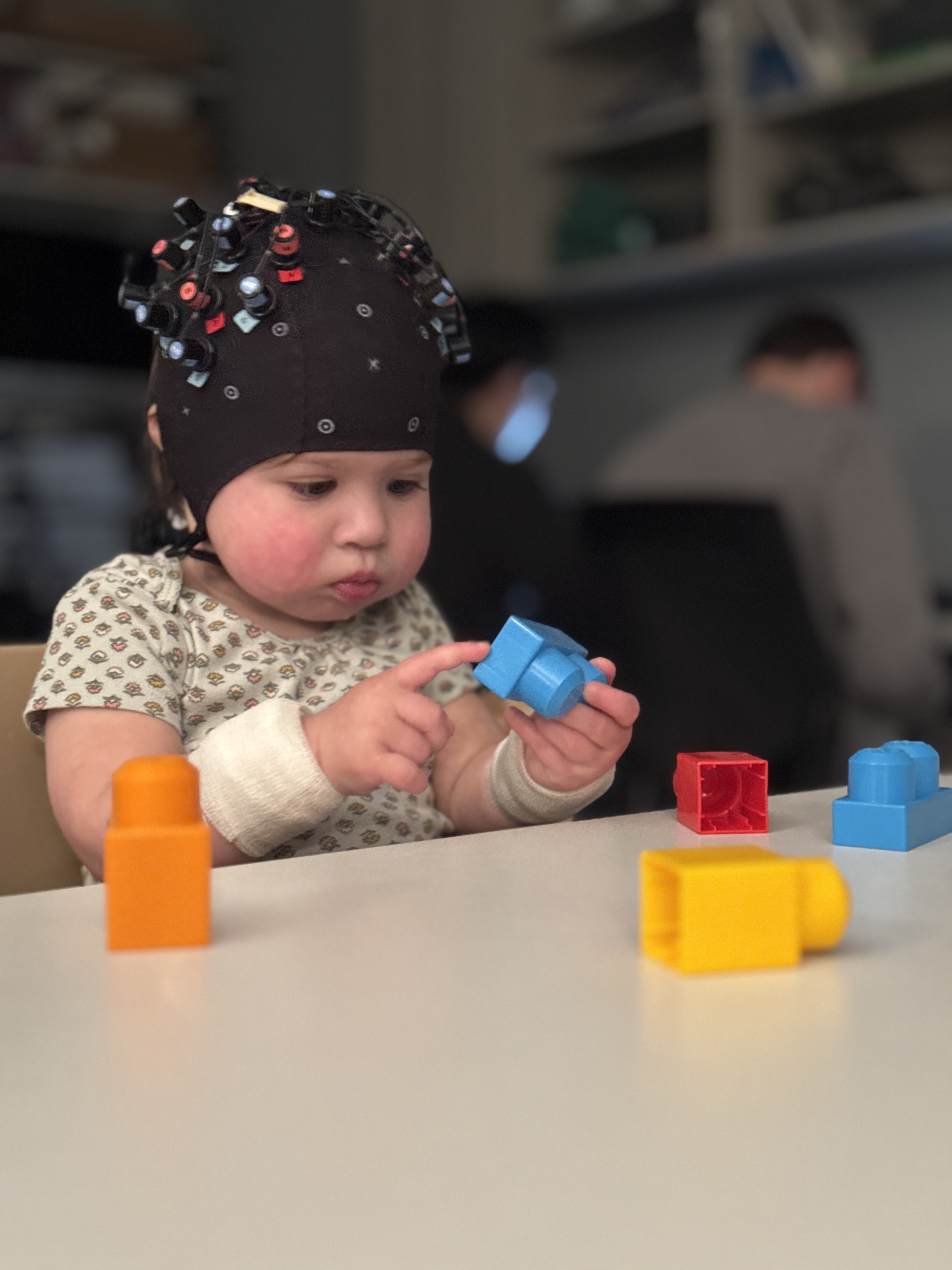 Infant with fNIRS cap playing with blocks