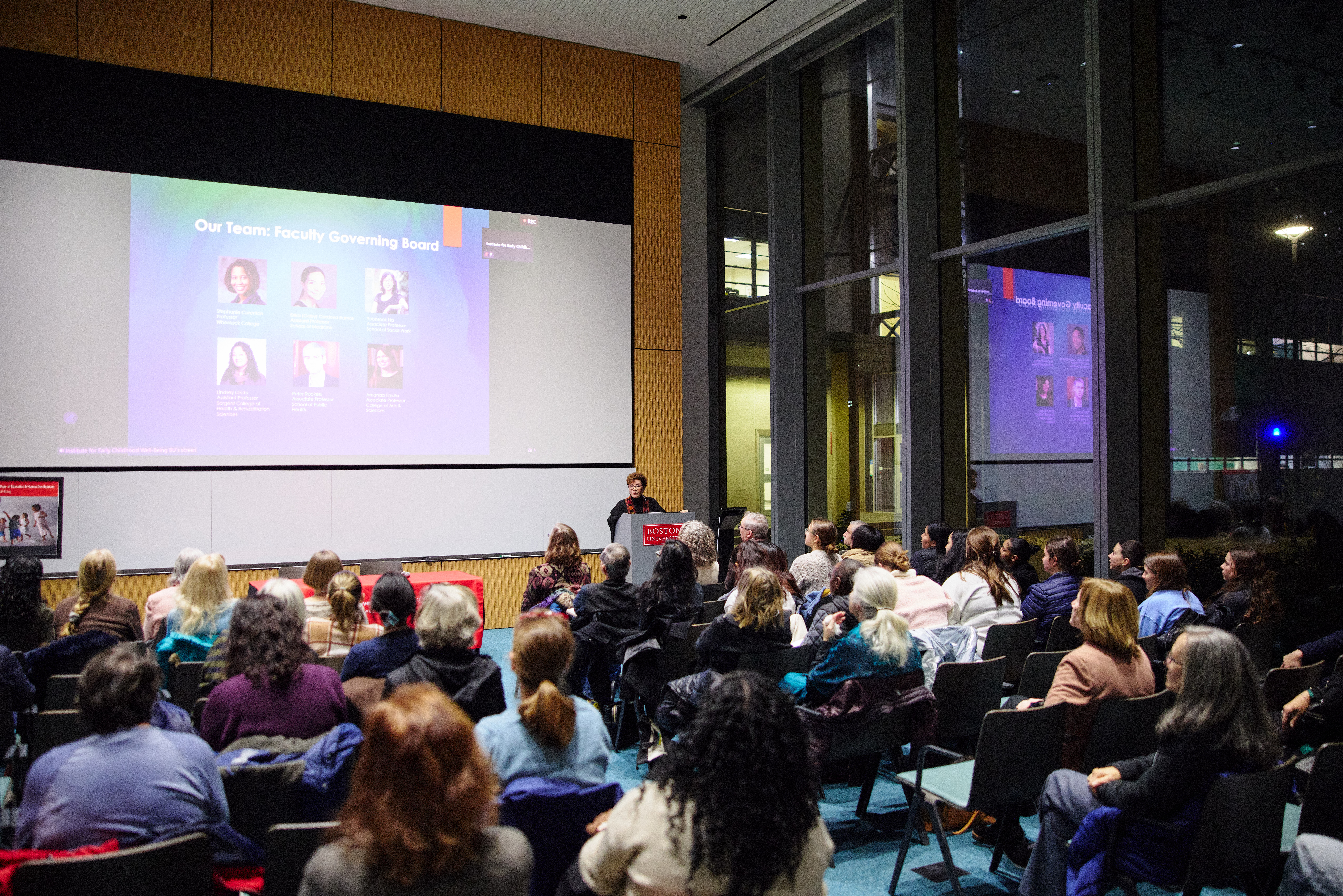 Attendees at the Institute for Early Childhood Well-Being keynote lecture, with a slide showing the Faculty Governing Board.