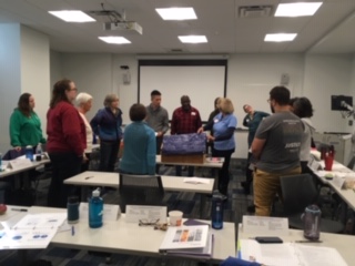 Participants surround a model house during the UMCOR disaster response training.