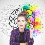 Teenager seated beside a wall painted with a colorful sketch of a brain