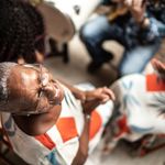Older woman playing music at home with family in the background