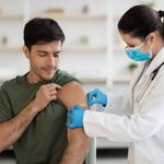 Healthcare professional administering a vaccine to a patient, who is rolling up their sleeve