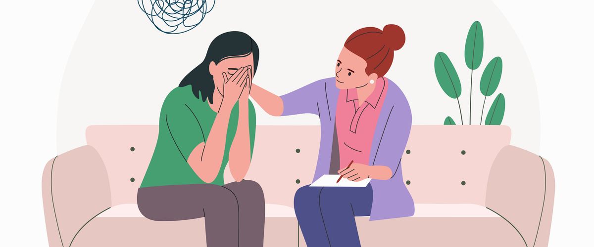 Illustration of a counselor sitting beside a distressed person on a couch, offering comfort as the person covers their face, with a scribble symbol above representing emotional distress.