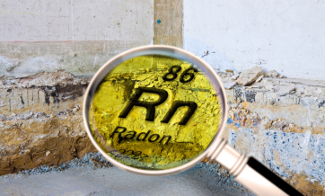 Magnifying glass highlighting the chemical symbol for radon (Rn) over a cracked basement wall and concrete foundation.