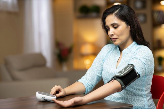 Woman taking her own blood pressure with a remote blood pressure cuff.