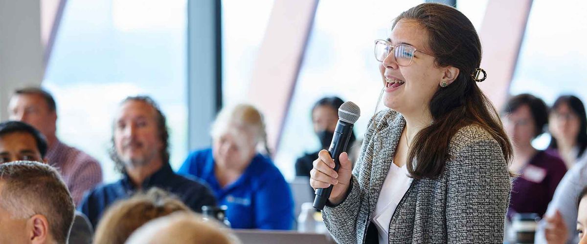 A conference participant asking a question to the presenter during a Q&A session
