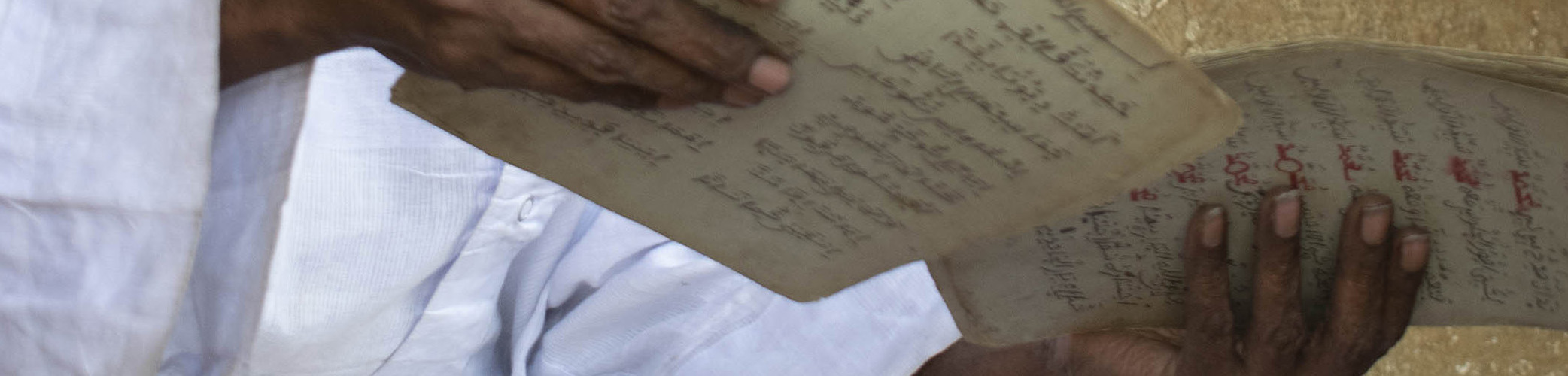 Late Ansou Daffe, a Mandinka scholar from Ziguinchor, ordering pages of an Ajami poem.