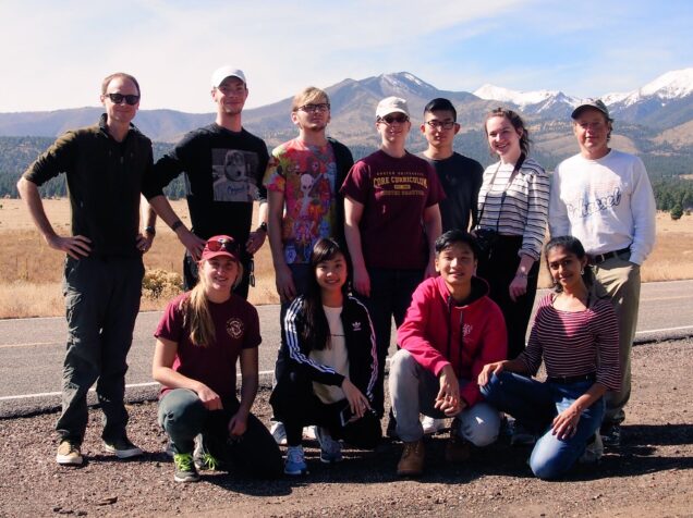 CC 111 students and faculty at Sunset Crater National Monument with the San Francisco Peaks (dormant volcano) in the background, Fall 2018.  Photo by P. Muirhead (far left standing).  Dr. A. Kurtz (BU Earth &amp; Environment, far right standing) and Dr. R. Stevens (BU Core Curriculum and Biology, standing middle) also joined for the trip.